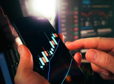 Cryptocurrency trading analysis mobile chart growth candlesticks. Close-up of hands analyzing bullish candlestick patterns on smartphone