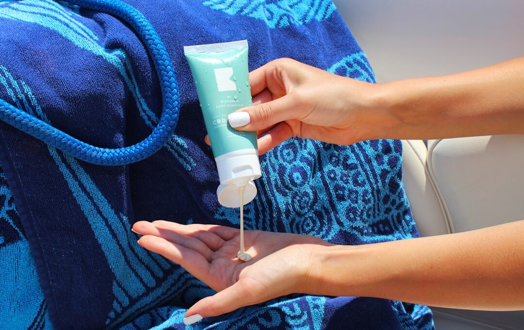 Squeezing CBD lotion into cupped hand on a boat with beach towel and rope