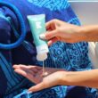 Squeezing CBD lotion into cupped hand on a boat with beach towel and rope