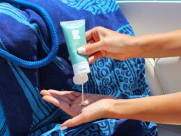 Squeezing CBD lotion into cupped hand on a boat with beach towel and rope