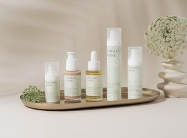 A beautifully arranged display of elegant skincare products on a marble tray against a soft, beige backdrop. The collection includes various bottles and jars, showcasing a range of serums, creams, and SPF protection. The minimalist design and soft pastel colors create a clean, luxurious aesthetic. A delicate floral arrangement in a textured vase adds a natural touch to the composition, enhancing the serene and sophisticated vibe.
