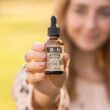 Vrouw houdt een flesje CBD-olie vast